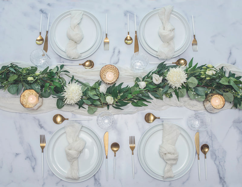 White modern plates, gold and white flatware, and soft linens fill the table